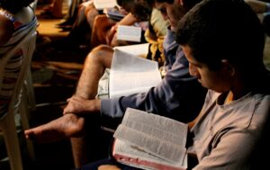 Estudantes com bíblia e apostila aberta em IPL