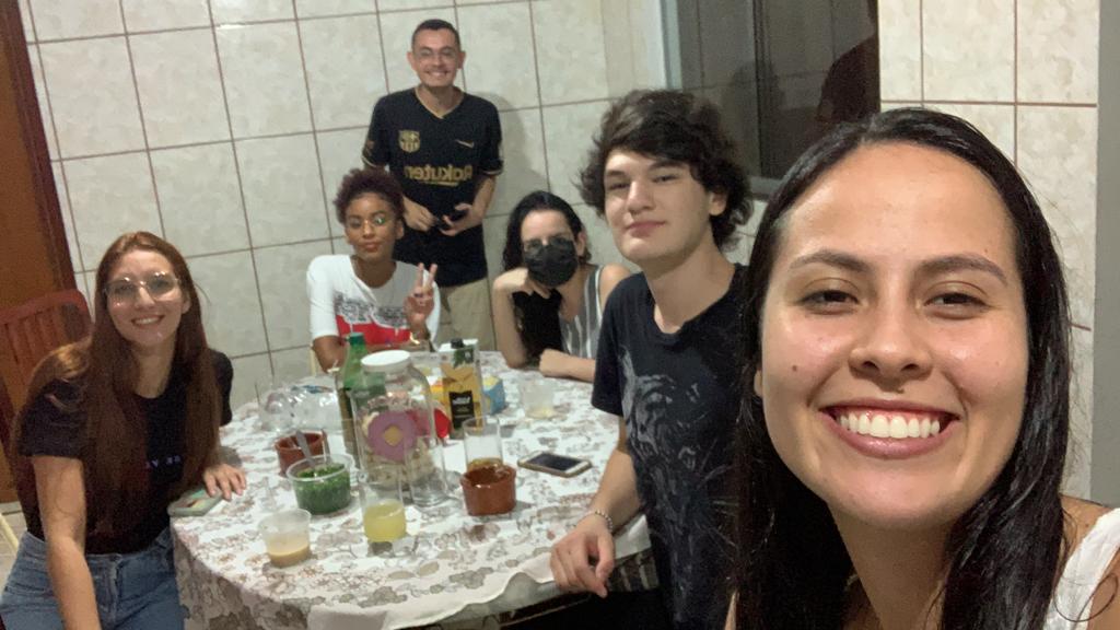 Estudantes ao redor de uma mesa sorriem pra foto durante viagem missionária em Minas Gerais