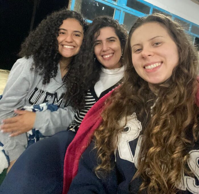 emaus-mentoria-pesquisa-fe-ciencia Duas participantes e uma mentora do projeto Emaús sorriem para a foto